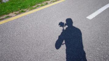 Man operator moves camera filming asphalt road near meadow video
