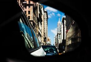 A car mirror showing a city street with buildings in the background photo