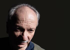 An older man with a mustache and a gray sweater photo