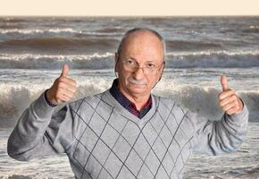 A man standing in front of the ocean giving a thumbs up photo