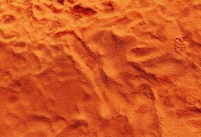 An orange sand texture with a few small footprints photo