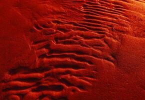 A red sand surface with footprints in it photo