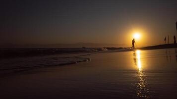 A person standing on a beach at sunset photo