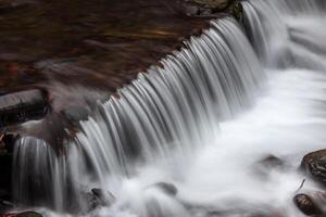 A waterfall flowing over rocks in a stream photo