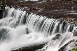 A man is standing on a rock next to a waterfall photo