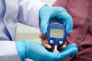 Asian doctor using digital glucose meter for check sample blood sugar level to treatment diabetes. photo