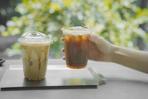 hand of woman holding a take-out iced lychee americano on black table at coffee shop. photo