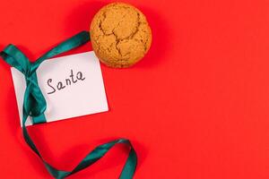 note to Santa with ribbon on red background with cookies, concept photo