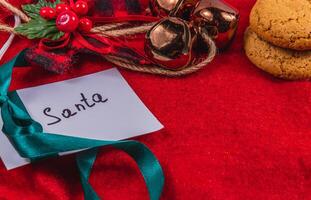 note to Santa on a red background with bells and cookies, concept photo