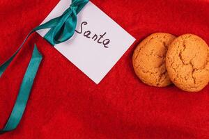 note to Santa with ribbon on red background with cookies, concept photo