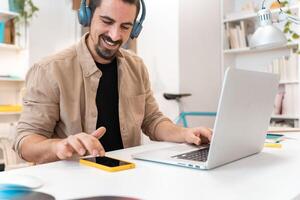 Smiling business man working on laptop at home office. Young student using computer remote studying photo