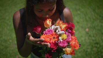 A Woman Gracefully Holding a Bright and Colorful Flower Bouquet Surrounded by a Lush Green Setting video