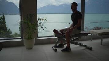 A man is exercising with a dumbbell while enjoying a stunning scenic view of a tranquil lake video
