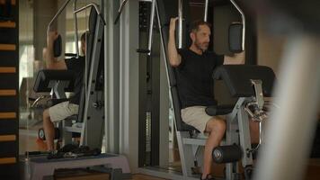 A dedicated man is utilizing a hightech exercise machine in a modern gym environment video