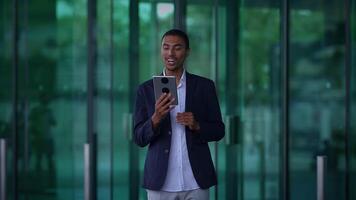A Smiling Young Man Engaging in an Exciting Call While Enjoying the Outdoors video