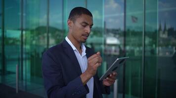 A skilled professional man is using a tablet in a modern urban setting with city features video