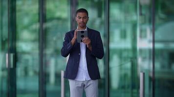 A successful businessman is utilizing a tablet in a contemporary urban business setting video