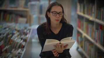 un mujer profundamente comprometido en su leyendo mientras rodeado por incontable libros en un biblioteca video