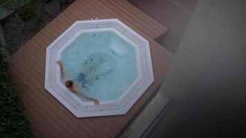 Enjoying a deeply relaxing moment in a luxurious hot tub during a serene evening time video