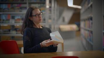 A student is browsing through a collection of books in a modern library environment video