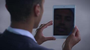 A Man Capturing a Selfie with a Tablet that Offers a Clear Reflection of His Face video