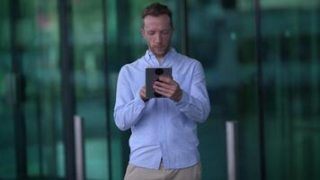 A Man Engaged in Using a Tablet While in an Urban Environment Surrounded by City Life video