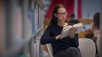 A woman is reading in a library, surrounded by shelves filled with books and literature video