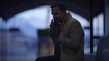 A man is talking on the phone while in an urban environment during the dusk hours video