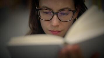A Focused Woman Deeply Engrossed in Reading a Book in a Cozy and Inviting Atmosphere video