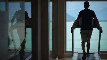 A man is actively exercising on a treadmill while enjoying a beautiful and scenic view video