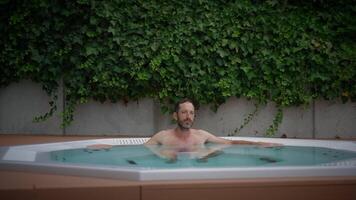 Relaxing in a hot tub amidst lush greenery, embracing calmness and serene bliss video