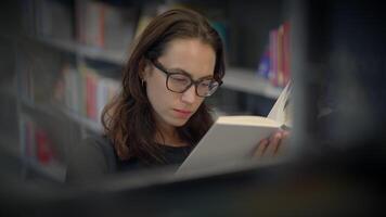 A Thoughtful Woman Immersed in Reading in a Peaceful Library Setting Surrounded by Books video