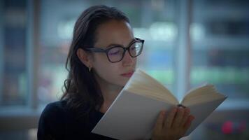 A Thoughtful Woman Engrossed in Reading a Book Within a Modern and Stylish Environment video