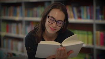 A woman is enjoying a captivating book in a cozy, warm, and charming library setting video