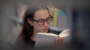 In a quiet library corner, a woman is engrossed in a captivating book, exploring knowledge video