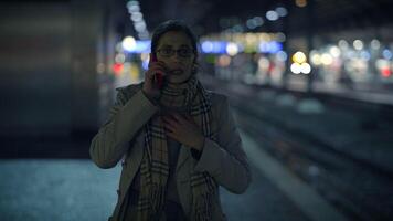 A woman talks on the phone at night in a vibrant urban setting with city lights video