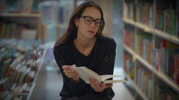A woman deeply engrossed in reading a book within the serene atmosphere of a library video