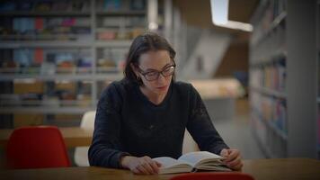 A Focused Reader Engaging with Books in a Contemporary Library Environment Setting video