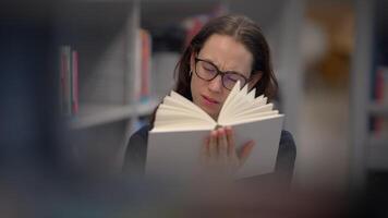 A woman deeply engrossed in reading a book in a quiet and serene library environment video