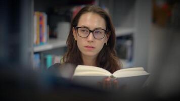 A young woman is reading an intriguing book in a cozy and inviting library atmosphere video