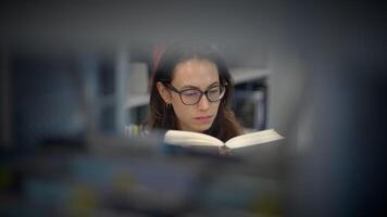 A dedicated and focused reader immersed in a tranquil library environment, exploring vast knowledge video