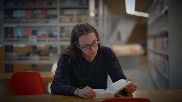 A Focused Reader Engaged in a Modern Library Setting with Abundant Resources and Calmness video