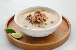 Coto Makassar, traditional food from Makassar, South Sulawesi. made from beef offal mixed with beef, seasoned with specially formulated spices. Usually served with Burasa or Ketupat or rice cake. photo