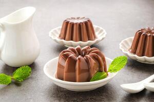 Chocolate pudding with mint leaf, served on a small white plate photo