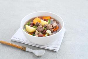 Sup daging kacang merah, clear soup with beef slices, red bean and vegetables. photo