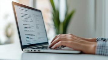 A close-up view of a person's hands typing on a laptop, accompanied by a green plant in the background, reflecting a modern workspace atmosphere. photo