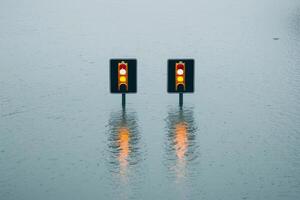 Traffic lights submerged in floodwaters, creating a surreal urban landscape. The reflection in the water enhances the impact of the scene, highlighting transportation challenges. photo