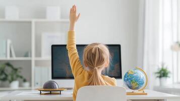 Child raising hand at computer, learning and engaging in online education, bright interior. photo