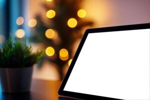 Blank tablet screen with a plant and blurred festive lights in the background. photo