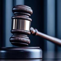 A wooden judge gavel on a reflective surface with dark background. photo